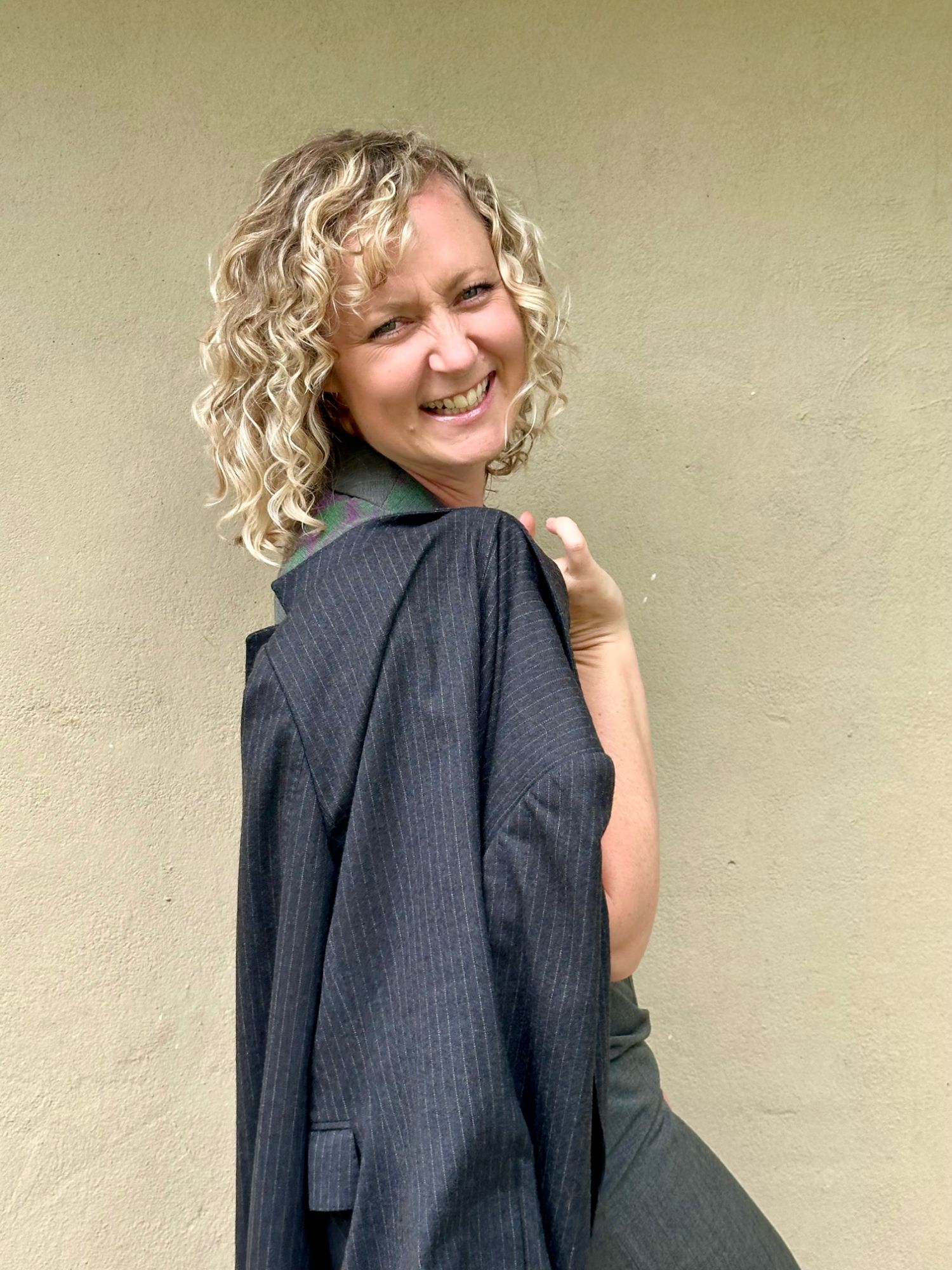 Paige Harkness glancing over her shoulder, in a pinstripe blazer